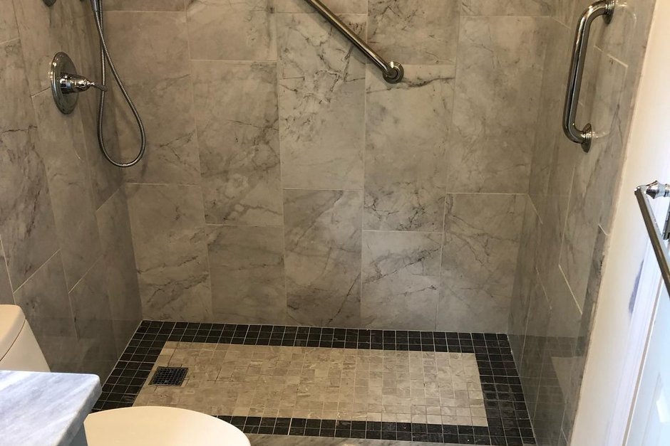 Tiled walk-in shower with a low curb and grab bars installed where a bathtub used to be in a small Long Island bathroom, by Just Enterprise One Corp.