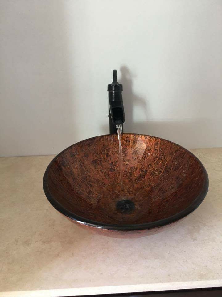 Amber vessel sink with waterfall faucet on stone vanity
