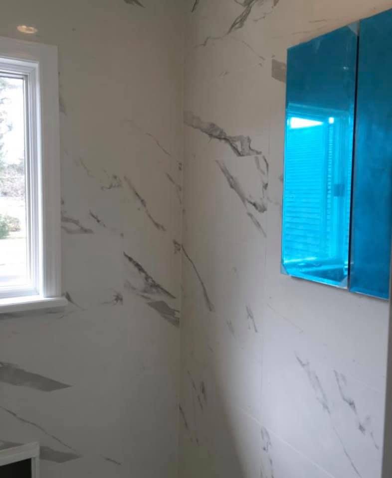 Marble tile walls with decorative blue mirror above vanity