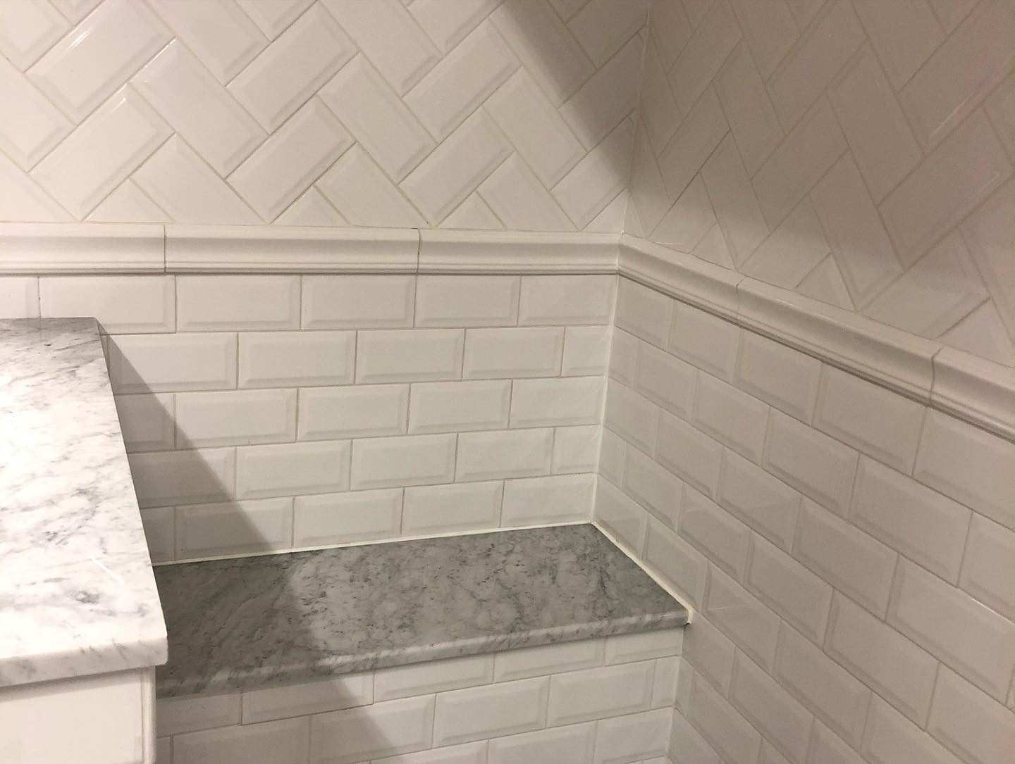 Herringbone white tile shower wall detail
