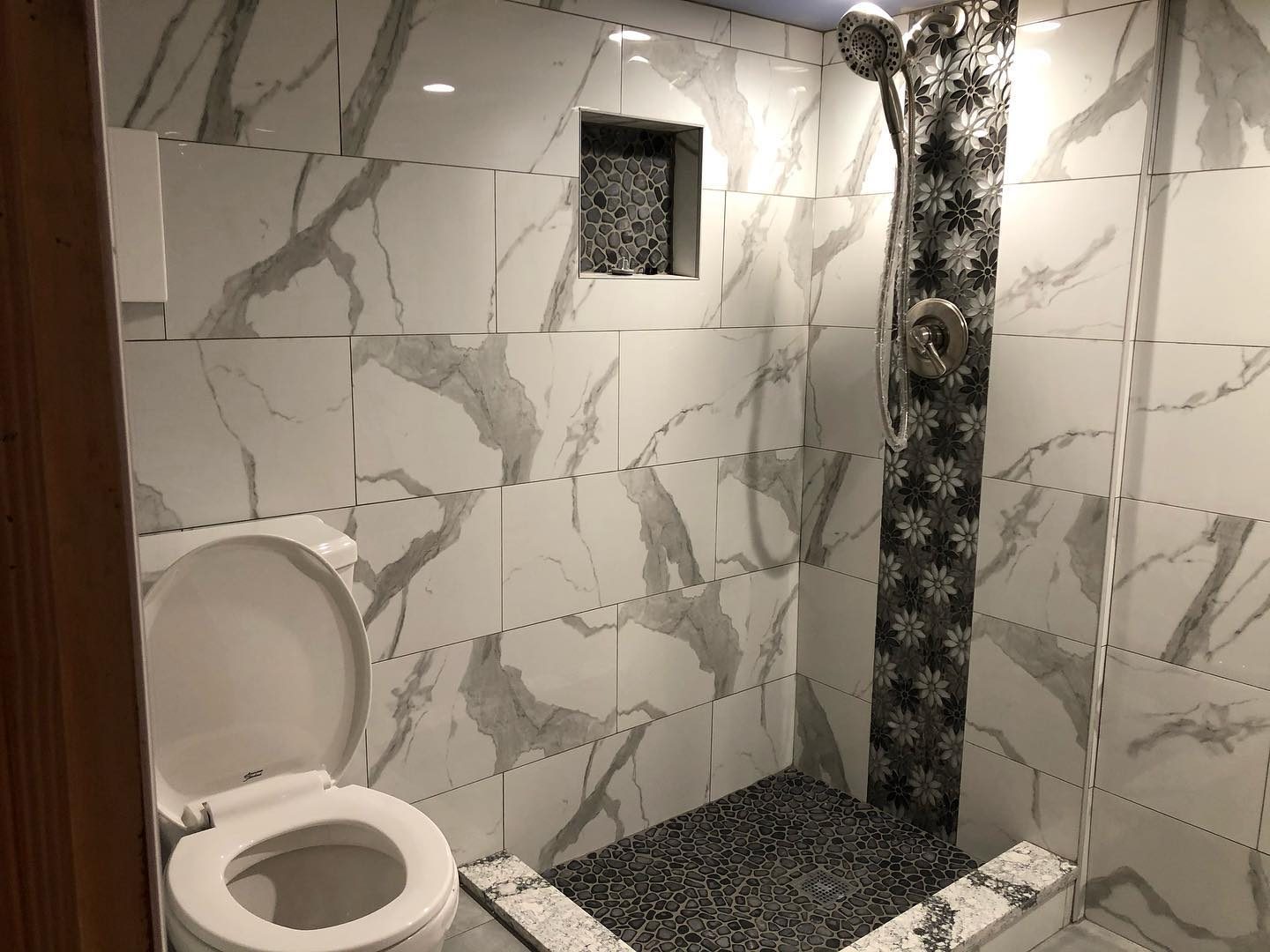 Full marble tile bathroom with decorative mosaic border