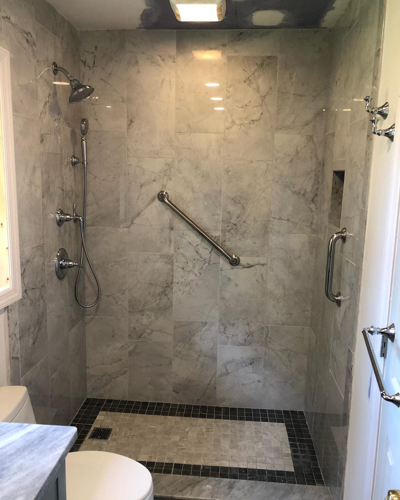 ADA-accessible marble shower with fold-down bench and grab bars