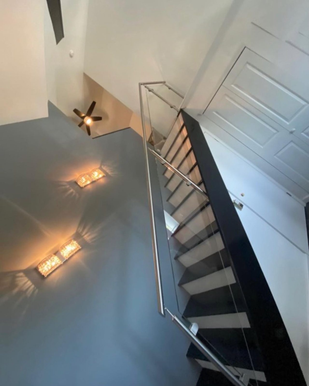 Modern floating staircase with glass and cable railing and LED sconces