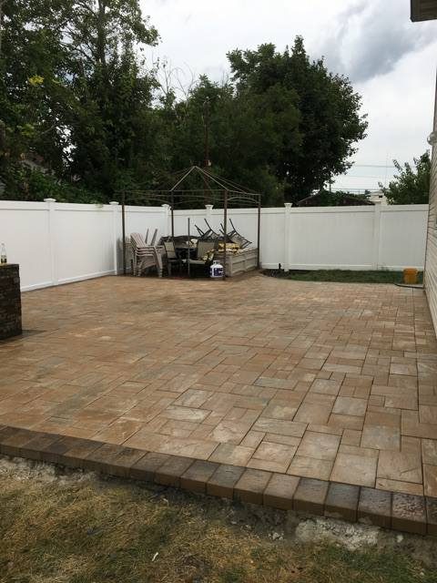 Tan paver patio installation with garden border