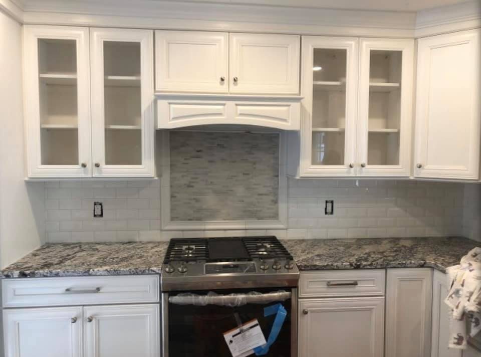 White cabinets with arched range hood and subway tile backsplash