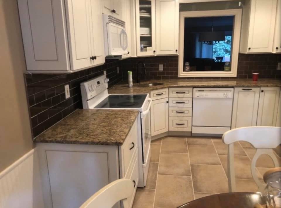 White kitchen cabinets with brown subway tile backsplash