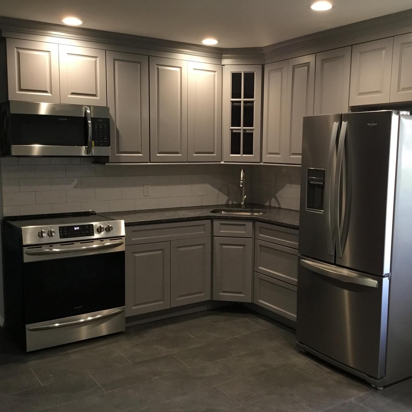 Gray raised-panel kitchen with quartz countertops and tile backsplash