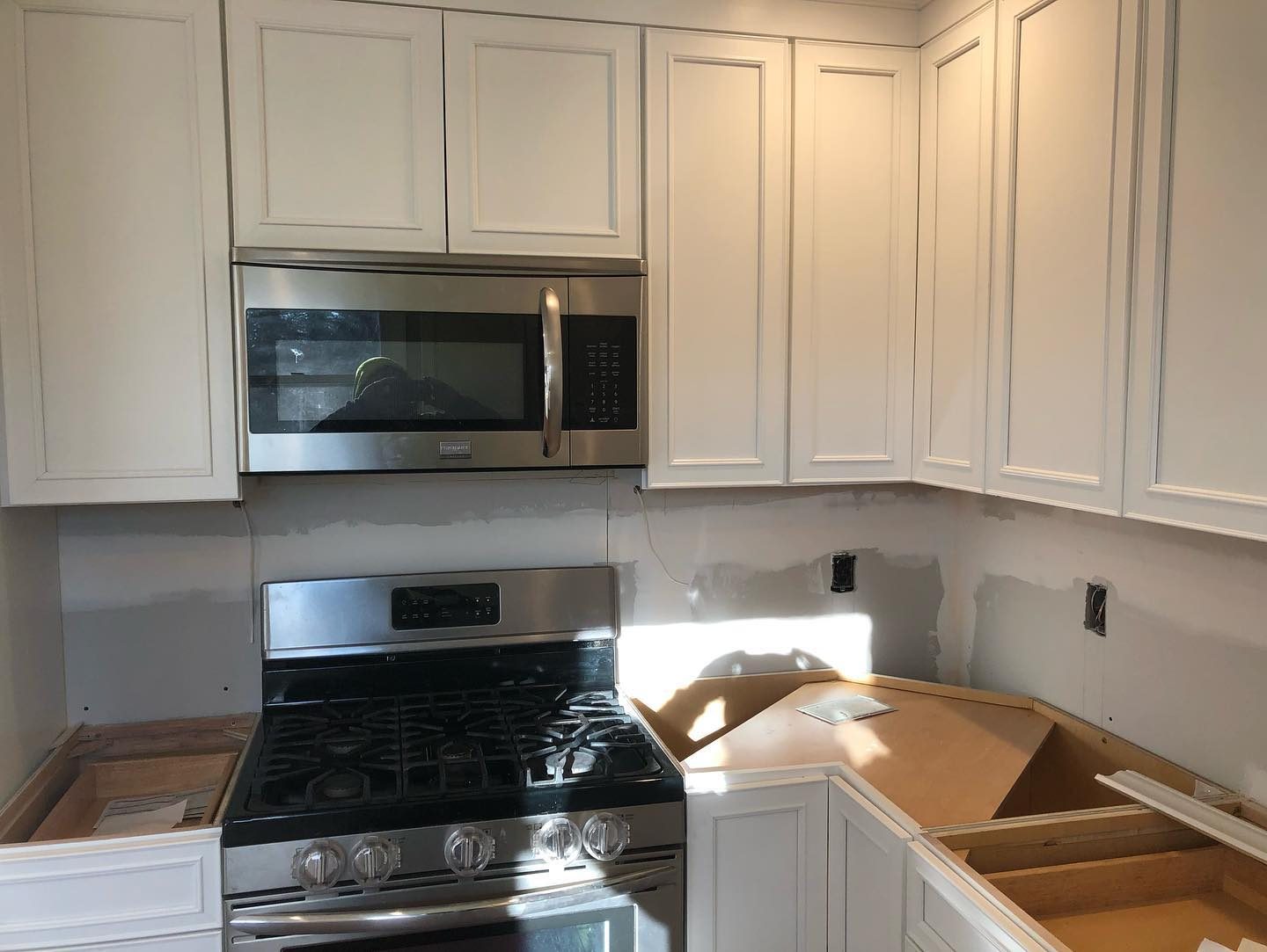 White kitchen renovation in progress — cabinet installation