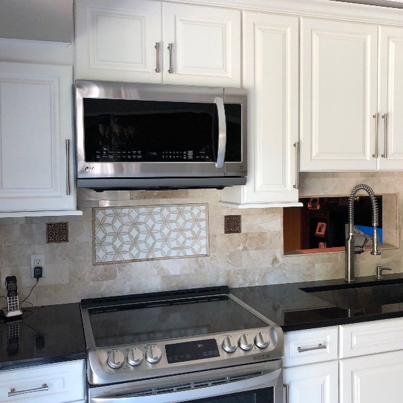White kitchen with arched window above sink and stone countertops