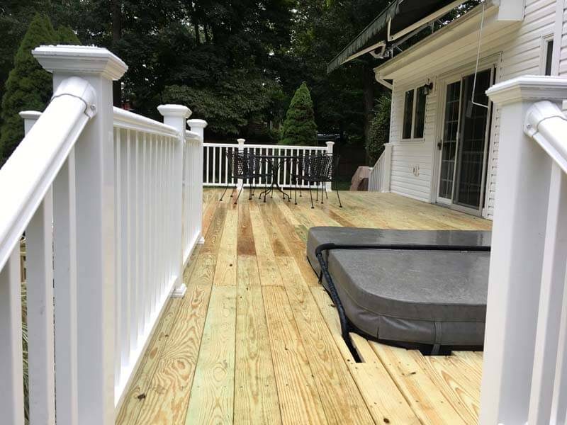 New wood deck with white railings and hot tub — West Babylon, NY