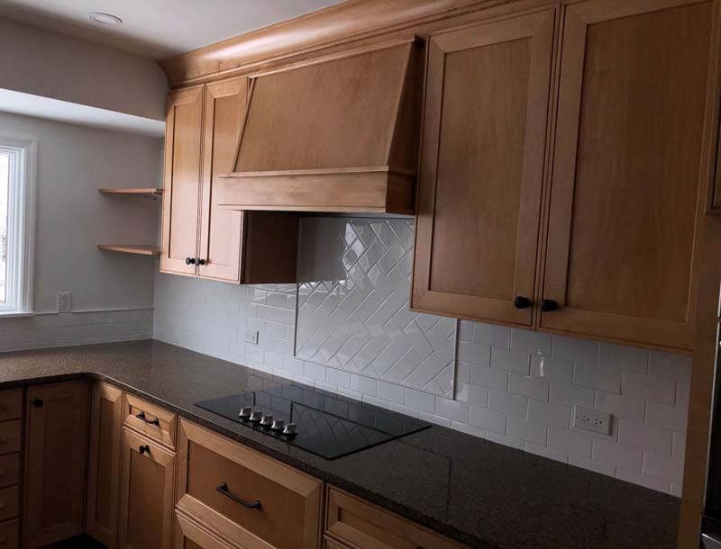 Natural wood cabinets with herringbone tile backsplash — West Babylon, NY